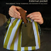 Hands place a spoon into the external pocket of a striped lunch bag for easy access to small items.