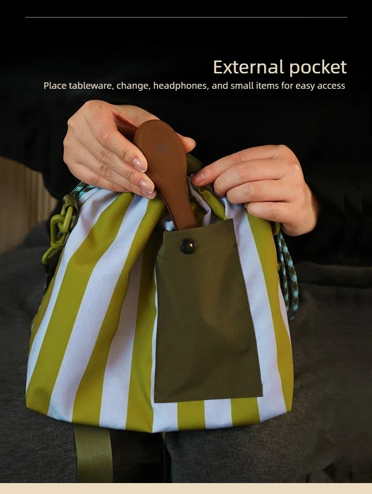 Hands place a spoon into the external pocket of a striped lunch bag for easy access to small items.