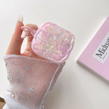 A hand holds a pink flower bowknot earphone case for AirPods against a white background.