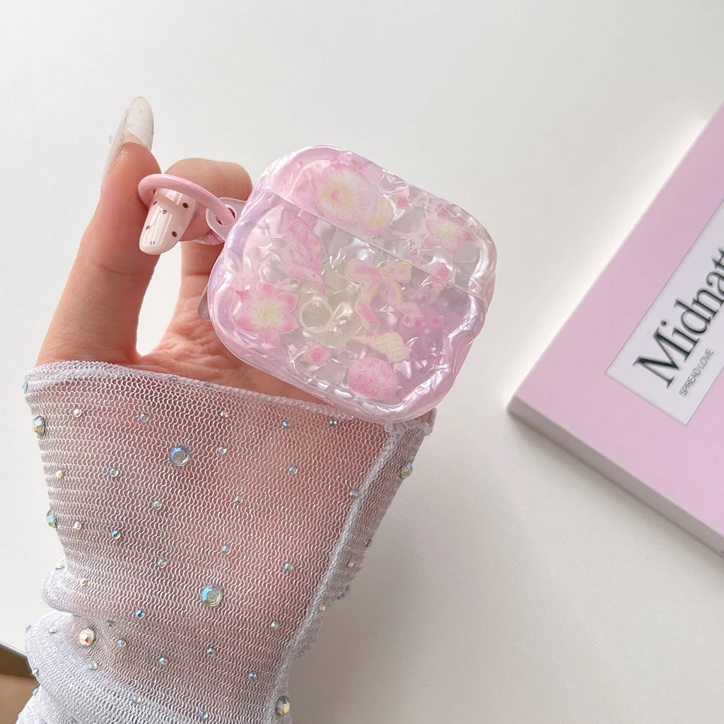 Une main tient une coque d'écouteurs en nœud floral rose pour AirPods sur un fond blanc.