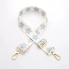 A beige nylon bag strap with a floral pattern and gold-toned hardware.