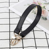 Black genuine leather replacement shoulder strap with gold hardware lying on a white checkered surface.