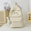 A beige embroidered backpack with a strap and pocket is displayed on a white surface.