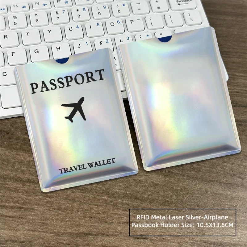 A passport holder with an RFID metal laser silver airplane design placed on a wooden desk next to a laptop keyboard.