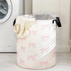A large, light pink fabric storage basket with pink bows is shown next to a white appliance.
