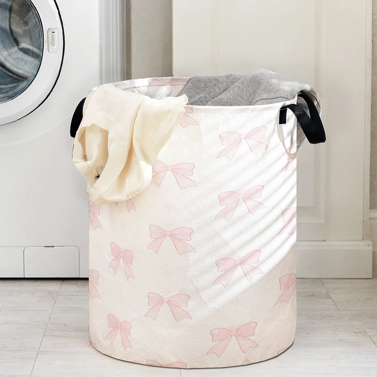 A large, light pink fabric storage basket with pink bows is shown next to a white appliance.