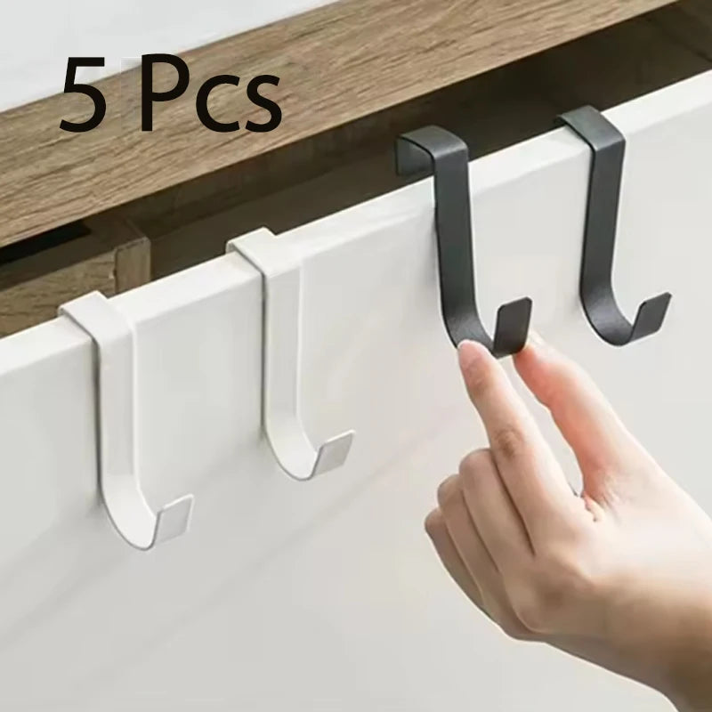 A hand is installing heavy duty multi-purpose hooks onto a white cabinet door using black metal hardware.
