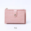 A pink mini crocodile pattern leather card holder with a zipper closure.