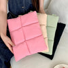 A stack of pink, beige, and green quilted laptop sleeves resting on a white surface.