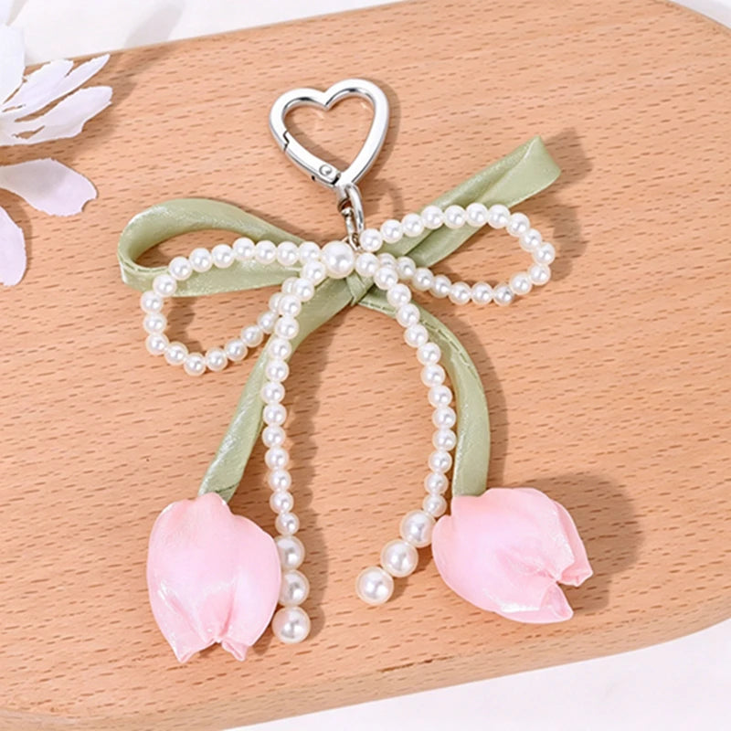 Aesthetic tulip flower bag charm keychain with a heart-shaped clasp and pearl strands on a light green ribbon.
