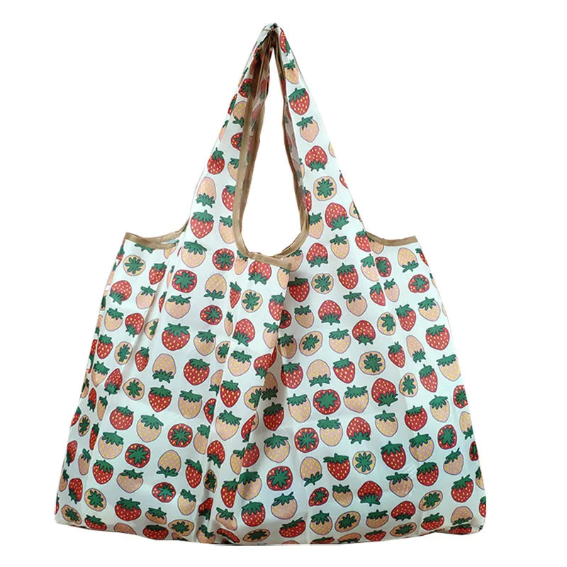 A reusable eco-friendly shopping bag patterned with strawberries and leaves.