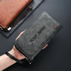 A dark gray leather wallet with custom name engraving is held in a hand, shown next to a black card sleeve.