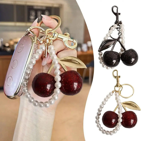 A close-up of a sparkling cherry resin keychain featuring dark red beads and gold accents.