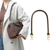 A brown patterned leather handbag with a long brown leather strap is held in a person's hand.
