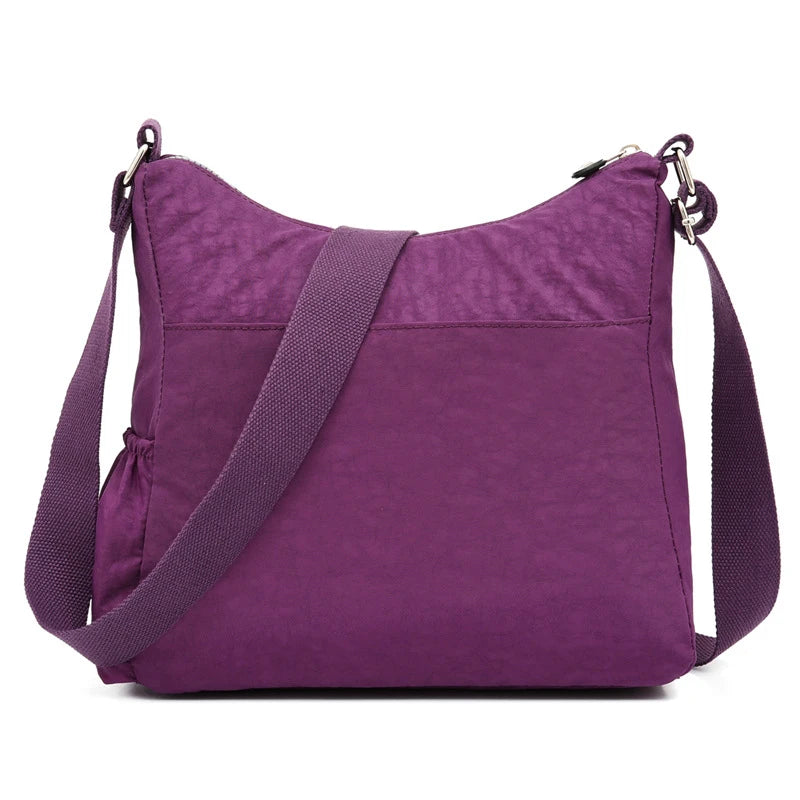 Lila wasserdichte Nylon-Crossbodytasche mit Trageriem auf weißem Hintergrund