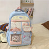 A light blue and pink Candy Color Campus backpack with a patterned fabric and storage pockets resting on a white surface.