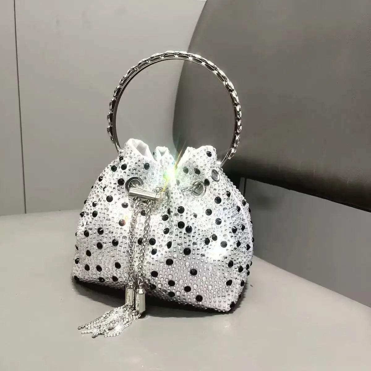A white clutch bag embellished with silver studs and featuring a gold-toned chain handle.