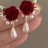 Gold-toned vintage velvet rose earrings featuring clear rhinestones and pearl drops.