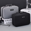 A black portable waterproof travel toiletry bag next to a grey one and a sink.