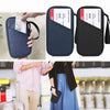 A black waterproof RFID blocking passport holder is shown being held and displayed next to a suitcase.
