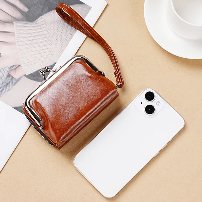 A brown vintage PU leather compact wallet with a leather strap resting on a beige surface next to a white smartphone.
