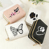 A collection of four heart-shaped zipper wallets featuring floral and butterfly prints in pink, black, white, and black.