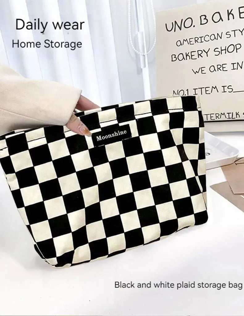 A black and white plaid storage bag is being held by a hand, displayed next to a sign for Uno Baker's.