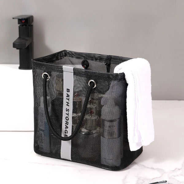 Black mesh drainage shower tote with a handle and a white towel resting inside.