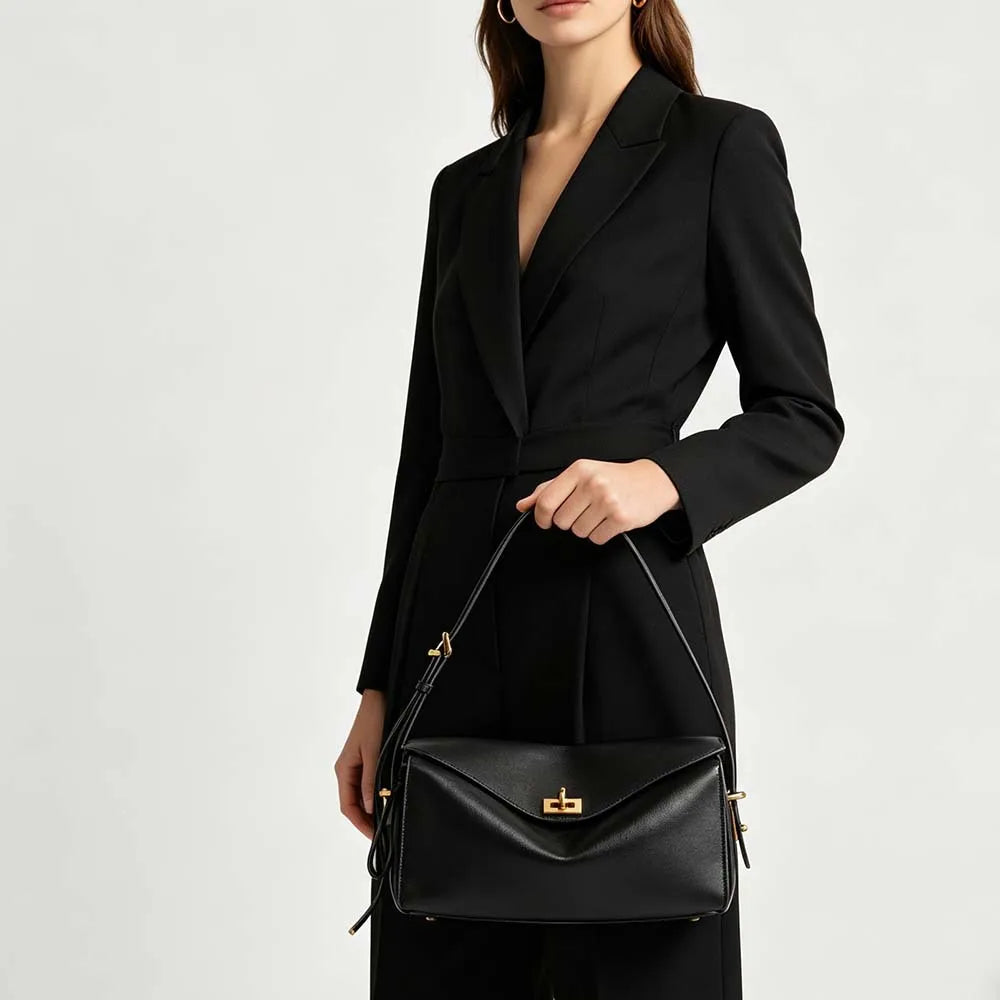 A woman wearing a black tailored blazer and black leather square shoulder crossbody bag.