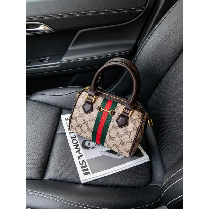 A beige and green striped leather tote bag with a brown strap resting on a black car seat.