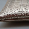 Close-up of a metallic silver alligator print clutch bag.