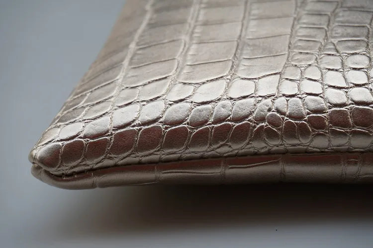Close-up of a metallic silver alligator print clutch bag.