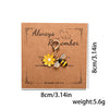 A gold-colored beaded flower keychain with a butterfly detail is displayed on brown kraft paper.