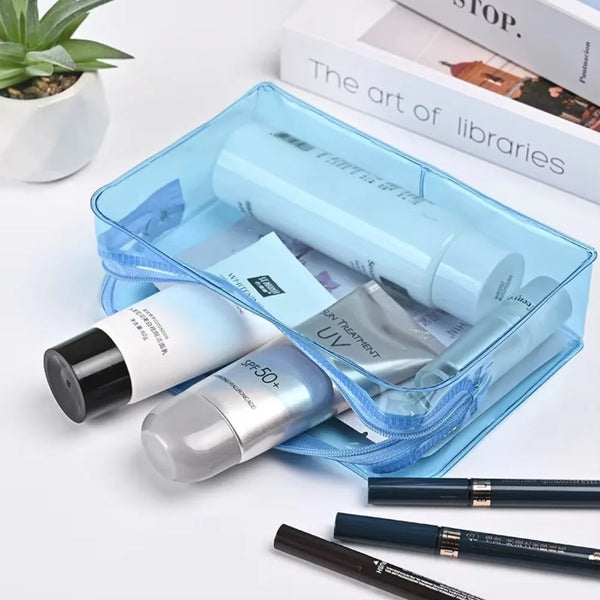 A transparent blue PVC travel makeup bag containing various cosmetic products and lipsticks.