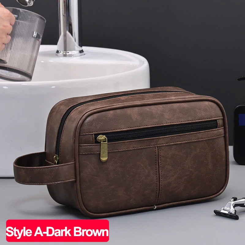 A dark brown PU leather travel toiletry bag resting on a gray surface next to a white sink.