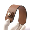 A brown leather carry loop for tote bags is being held by a hand.