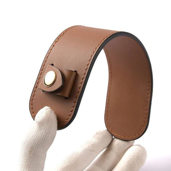 A brown leather carry loop for tote bags is being held by a hand.