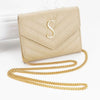 A beige quilted leather clutch with a gold chain strap and a silver initial S detail.