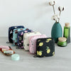 A collection of cute, floral-patterned sanitary pad storage pouches and a green glass jar with white cotton stems.