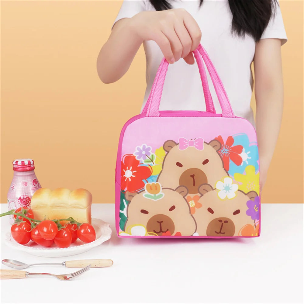 A pink insulated lunch bag featuring cute cartoon bears and flowers, held by a person.