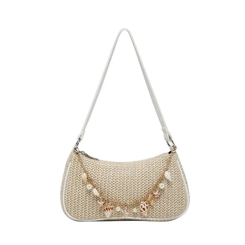 A beige straw shoulder bag featuring delicate ocean-themed charms and a thin strap.