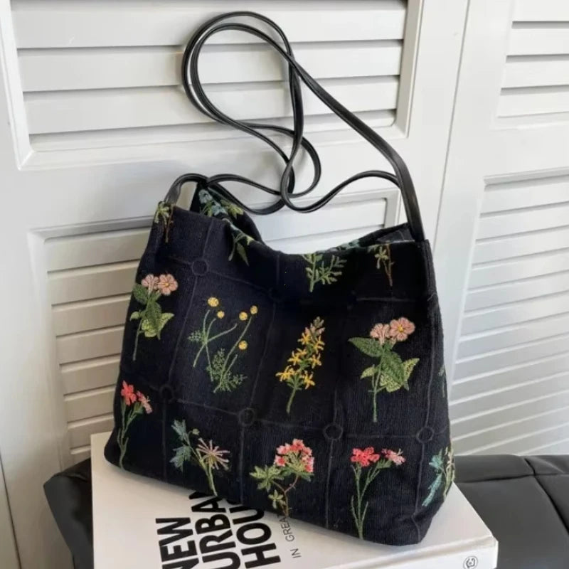Bolso de hombro jacquard de seda retro negro colgado en una puerta de madera ranurada blanca.