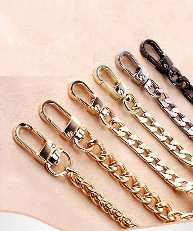 Several gold and black stainless steel diamond-cut curb chain bag straps are displayed on a light background.