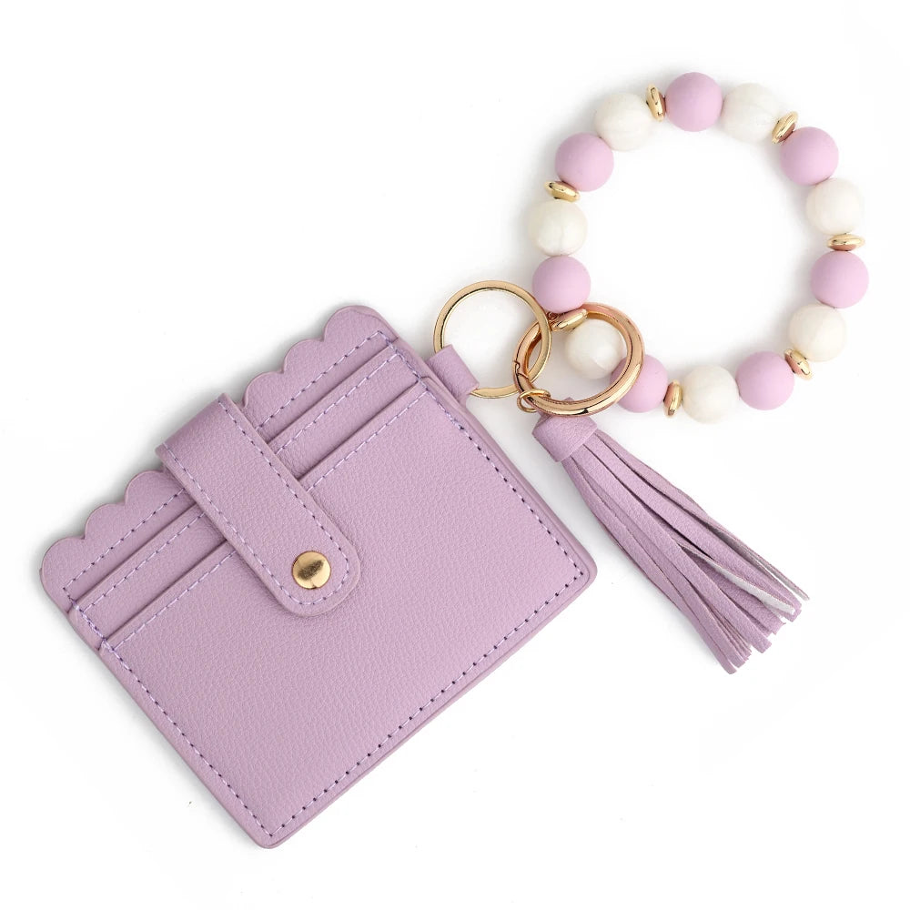 A purple silicone bead and leather card wallet with a white and pink beaded bracelet.