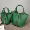 A deep green genuine leather bucket bag with a canvas strap and gold hardware.