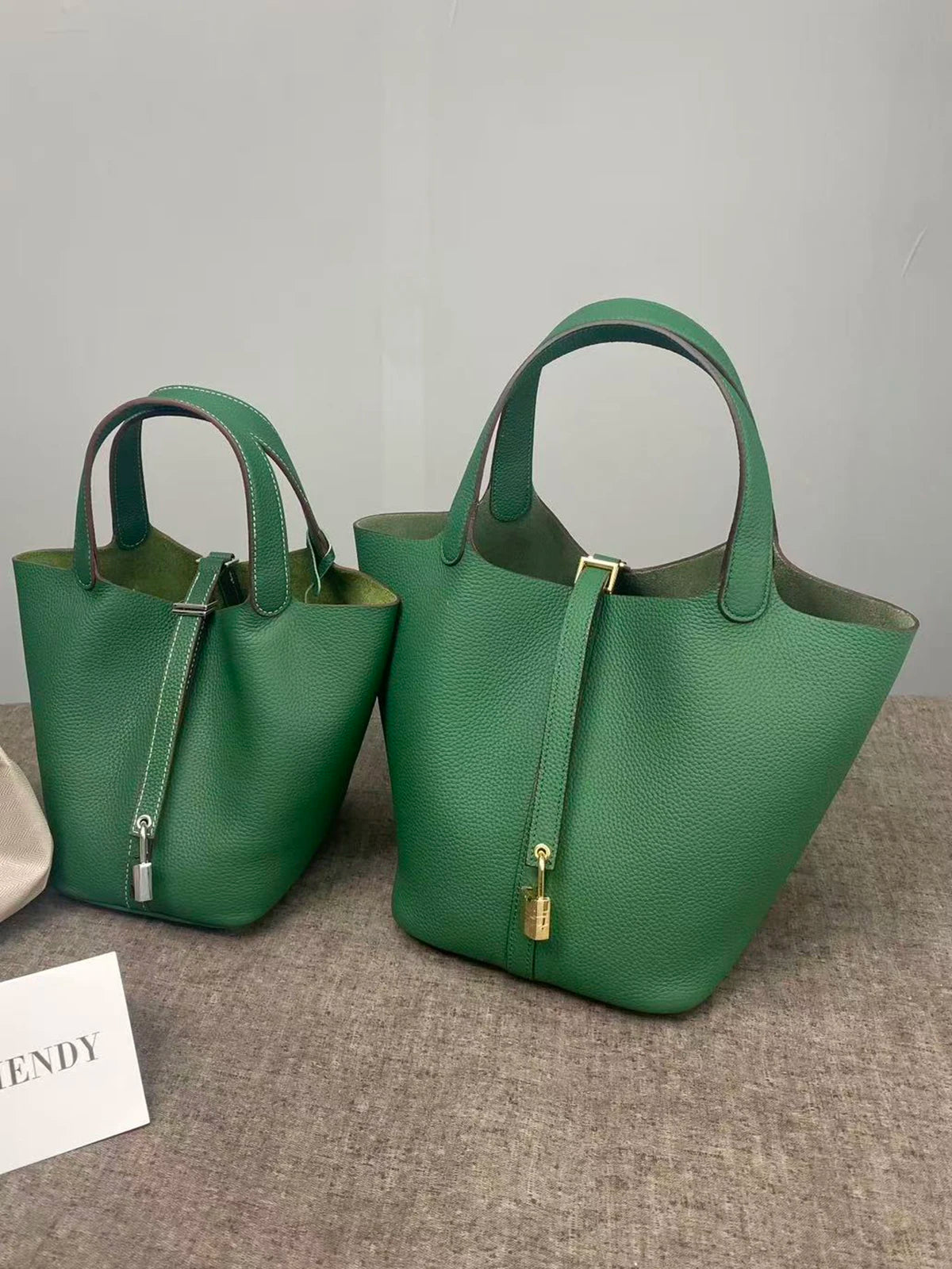 A deep green genuine leather bucket bag with a canvas strap and gold hardware.