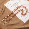 A delicate rose gold acrylic chain necklace laid on a piece of paper with text.