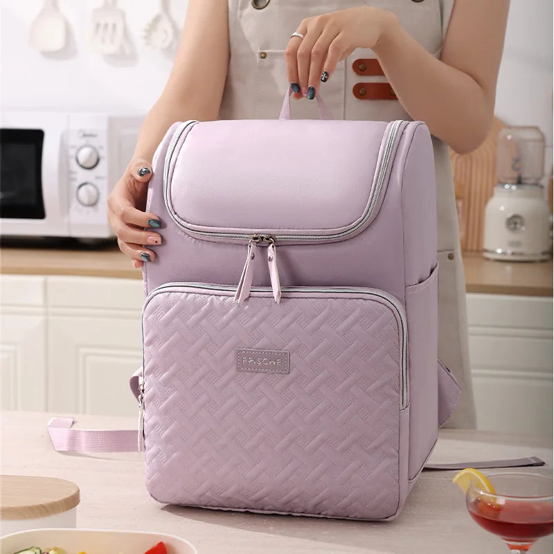 A light purple insulated picnic cooler backpack is shown being held by a person in a kitchen setting.