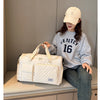 Eine Frau trägt eine beige Baseballkappe und ein graues Sweatshirt und hält eine weiße gesteppte Umhängetasche.