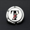 Silver foldable letter hanger hook with a floral design on a black background